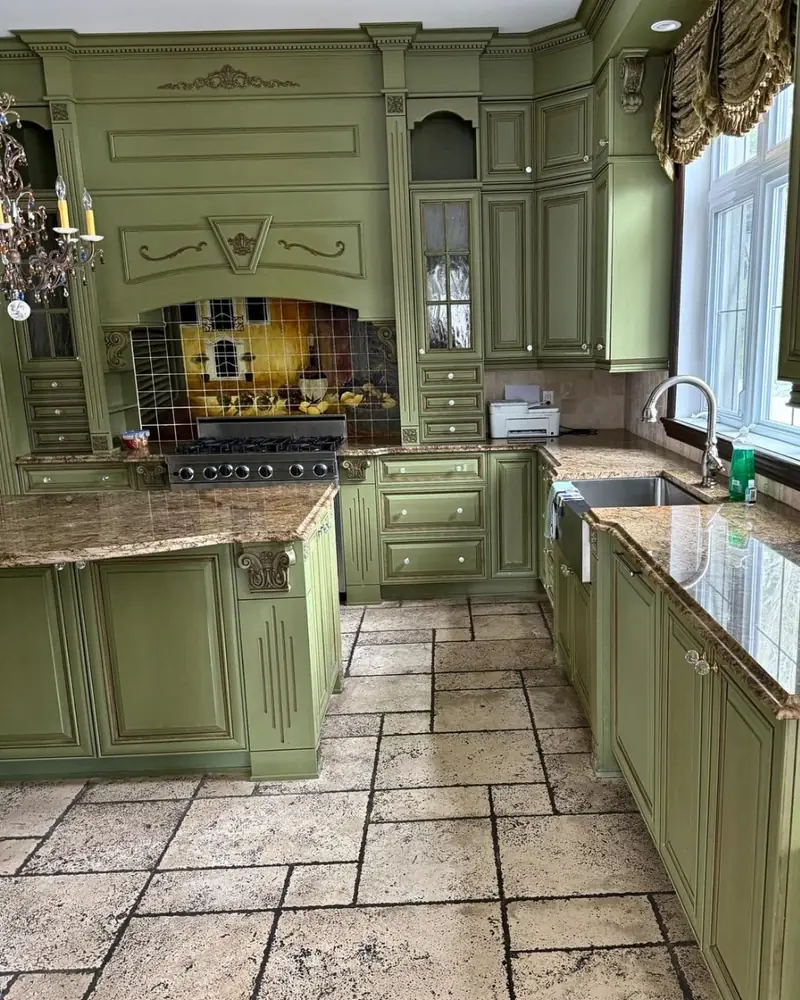 Cuisine avant : armoires vertes à moulures, hotte décorée et comptoir de granit